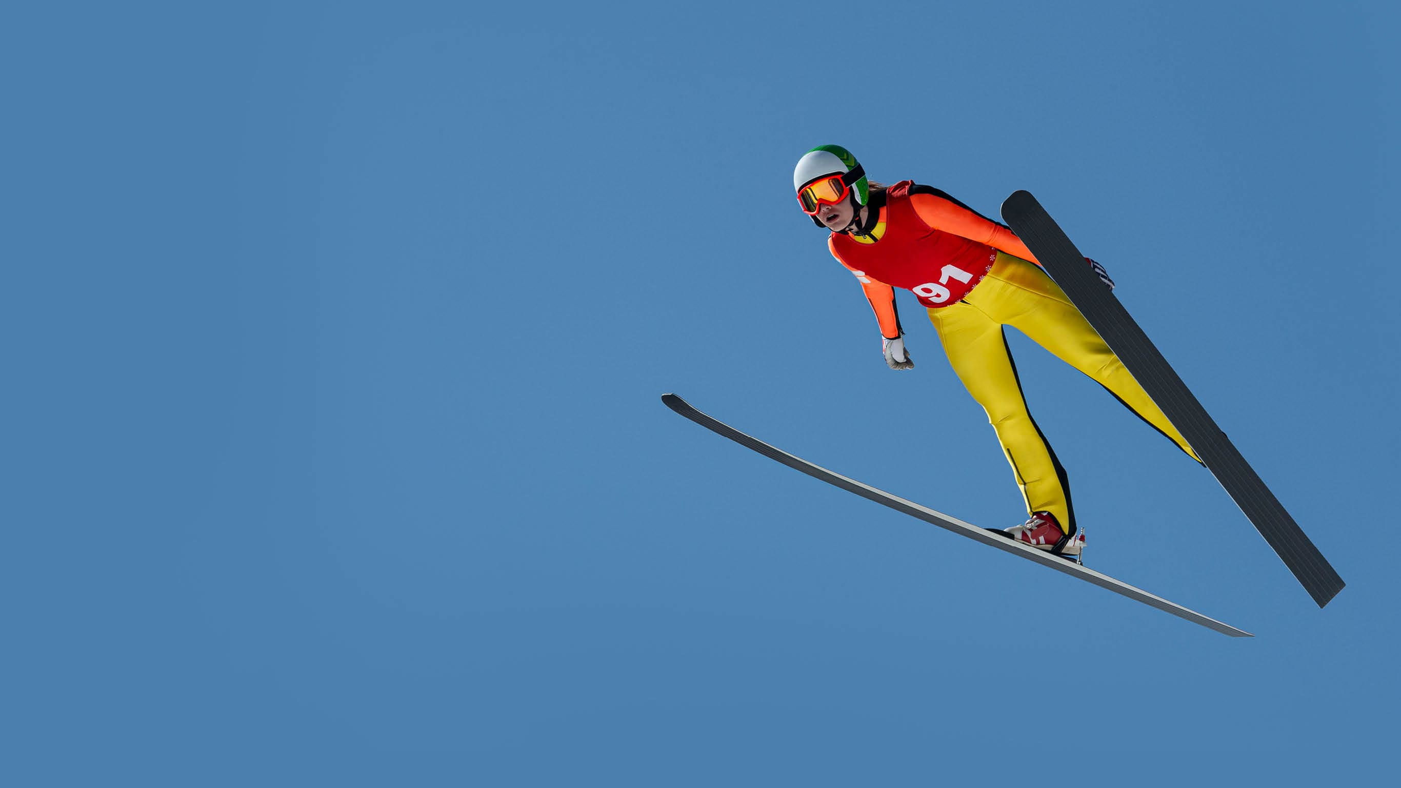 Front view of young female ski jumper during the long ski jump