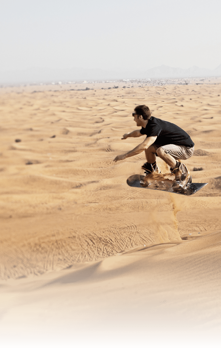25 year old man sand boarding on the sand dune called Big Red in the desert near Dubai 