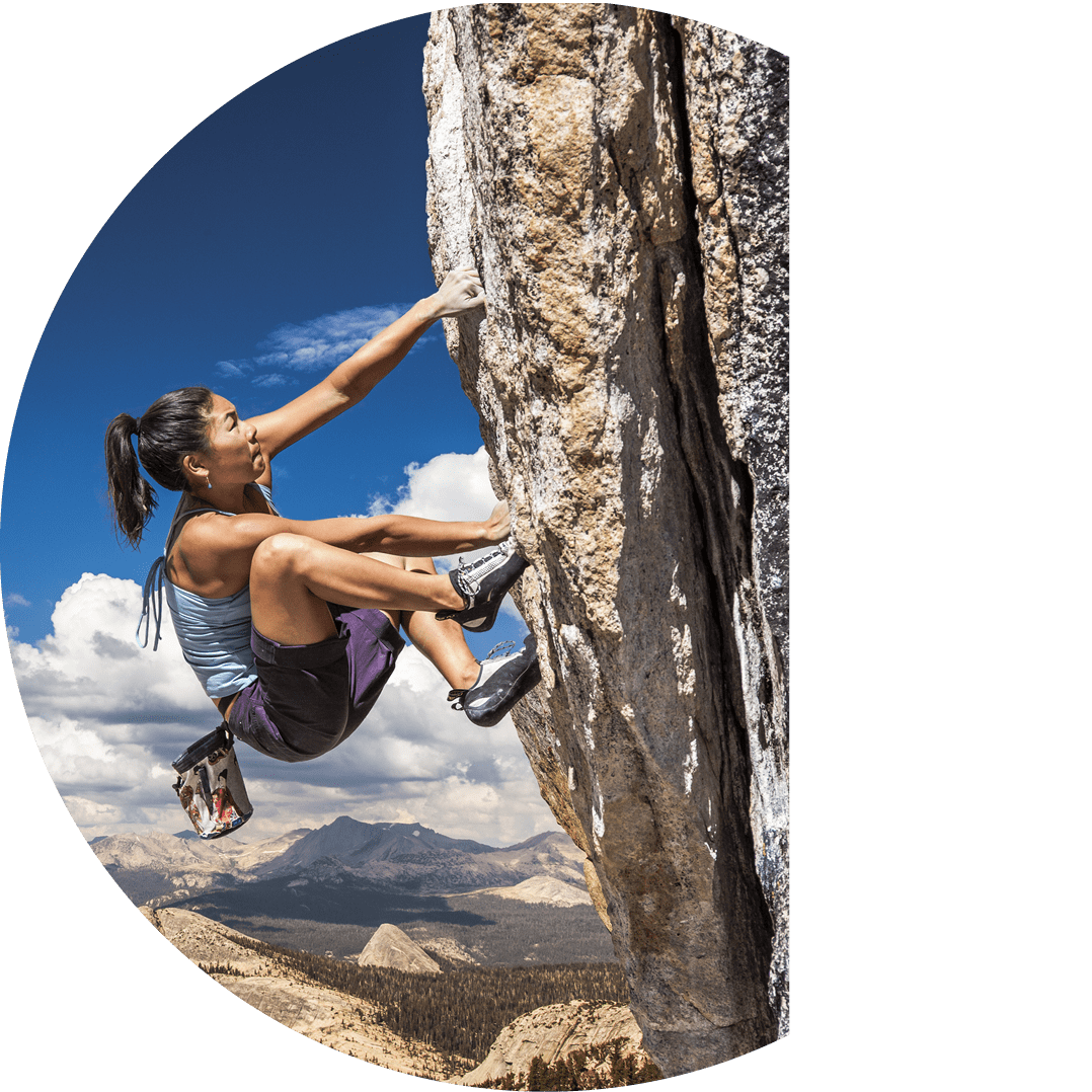 Female climber dangles from the edge of a challenging cliff 