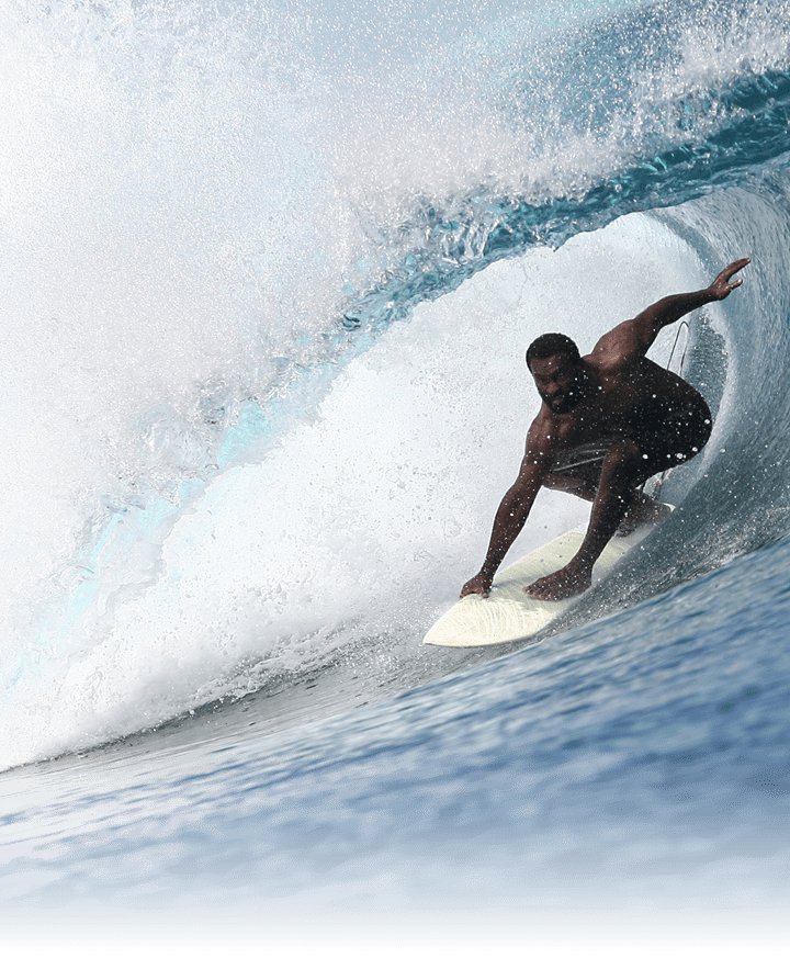 A fijian surfer rides under the lip of a breaking wave in Fiji