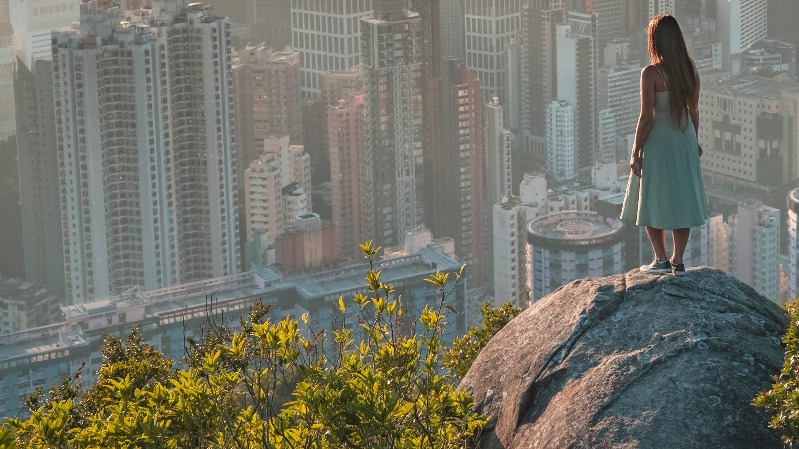 Girl standing on a rock while enjoying the beautiful and warm sunset over Hong Kong Island  The picture was taken on a November evening 