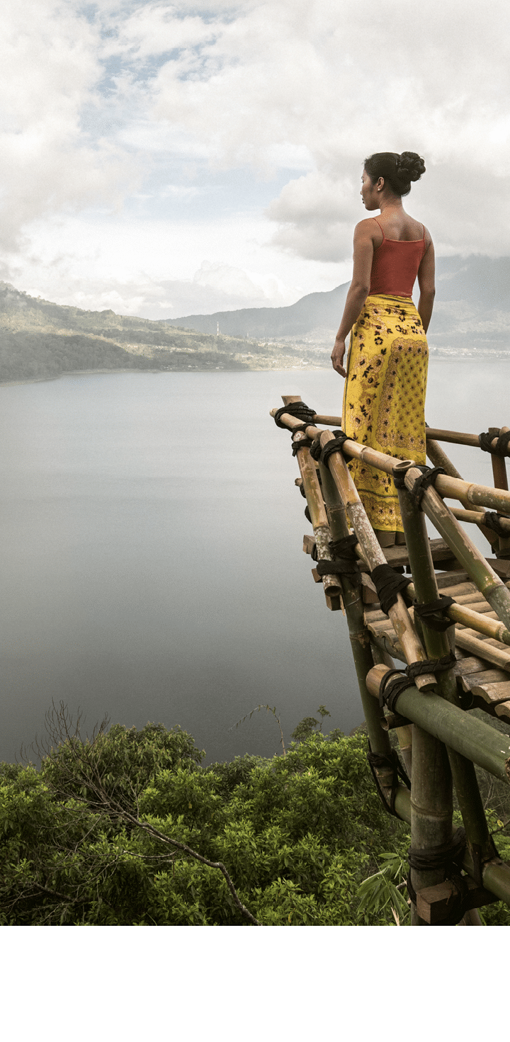 asia, indonesia, bali, an asian woman standing on a bamboo viewing platform, admiring the view of Danau Buyan lake below, through the clouds