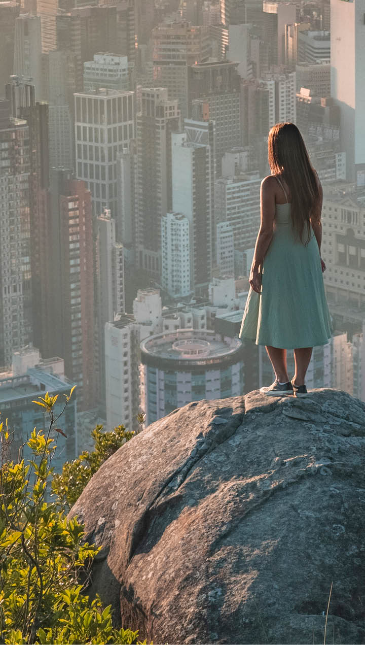 Girl standing on a rock while enjoying the beautiful and warm sunset over Hong Kong Island  The picture was taken on a November evening 