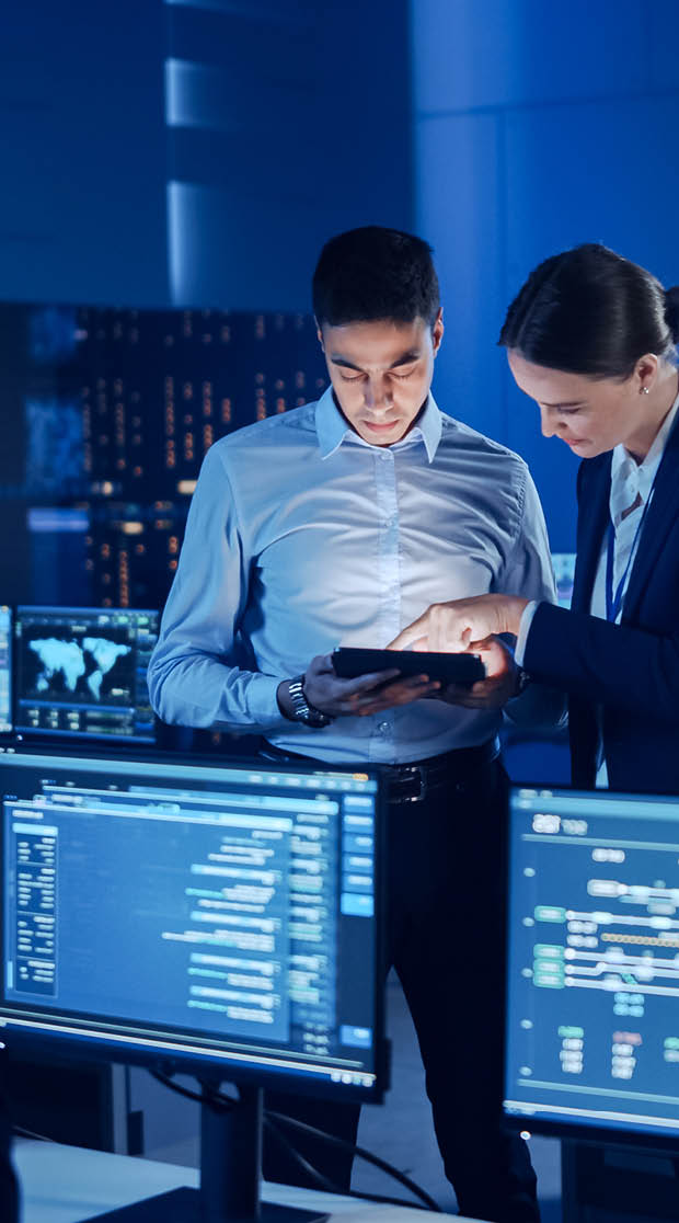 Project Manager and Computer Science Engineer Talking while Using A Digital Tablet Computer. Telecommunications Company System Control and Monitoring Office Room with Working Specialists.