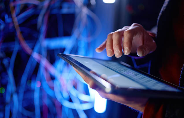 Closeup hands of data engineer working in digital tablet in supercomputer server room