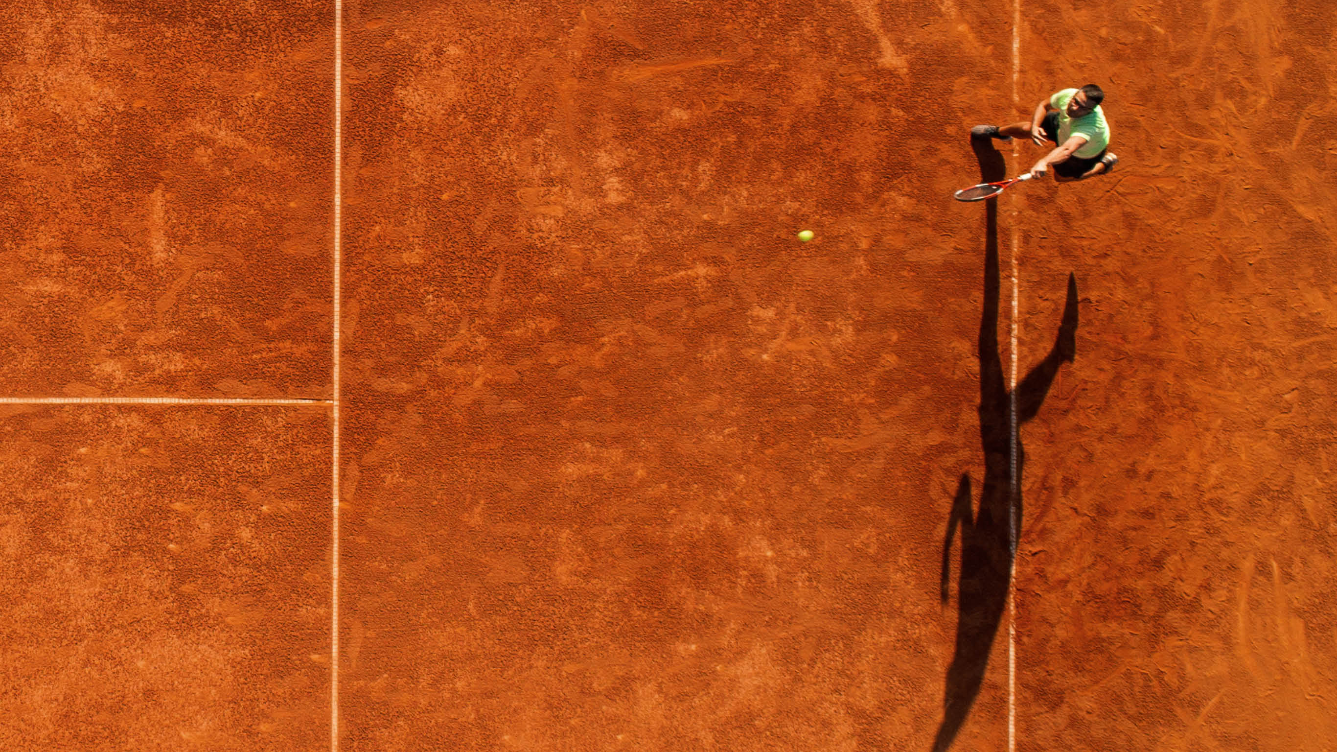 One part of tennis clay court with one man player only  He is mature adult, and very agile and healthy  Photo made with drone, directly above 