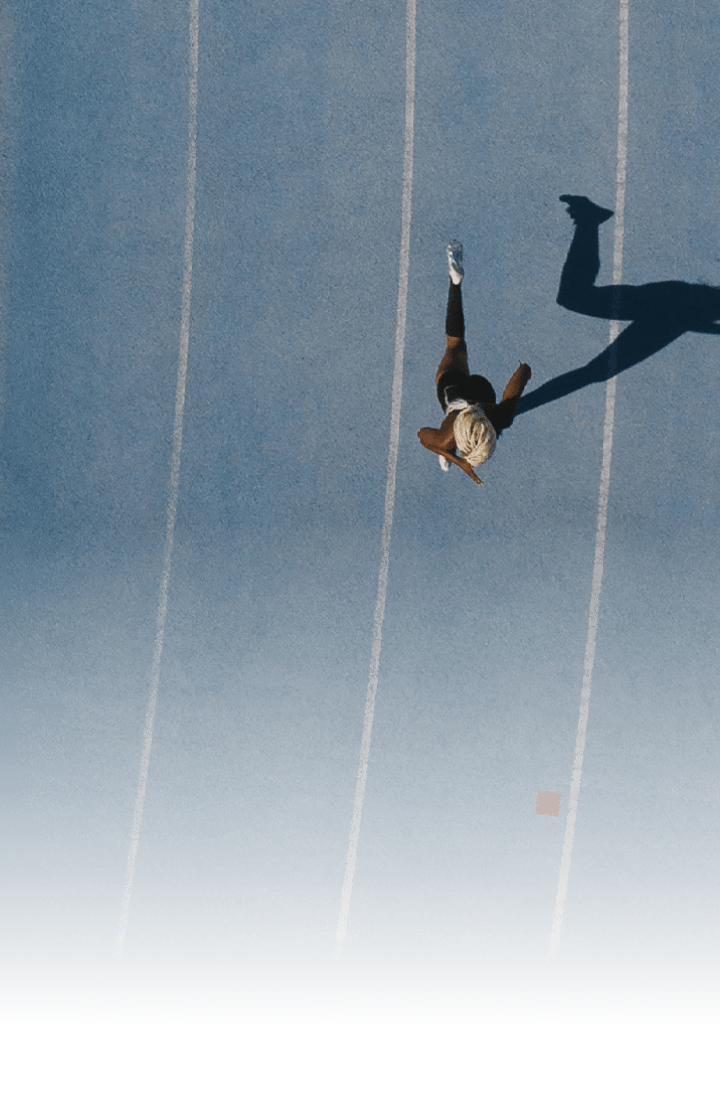 Sprinter running on athletic track  Top view of a sprinter running on race track in a stadium with shadow falling on the side 
