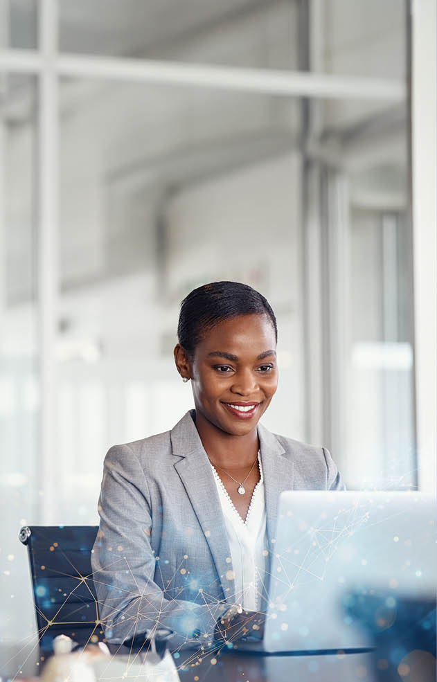 Happy black business woman working on laptop at modern office. Focused mature businesswoman checking email in meeting room with copy space. African american manager typing on a keyboard in her office.