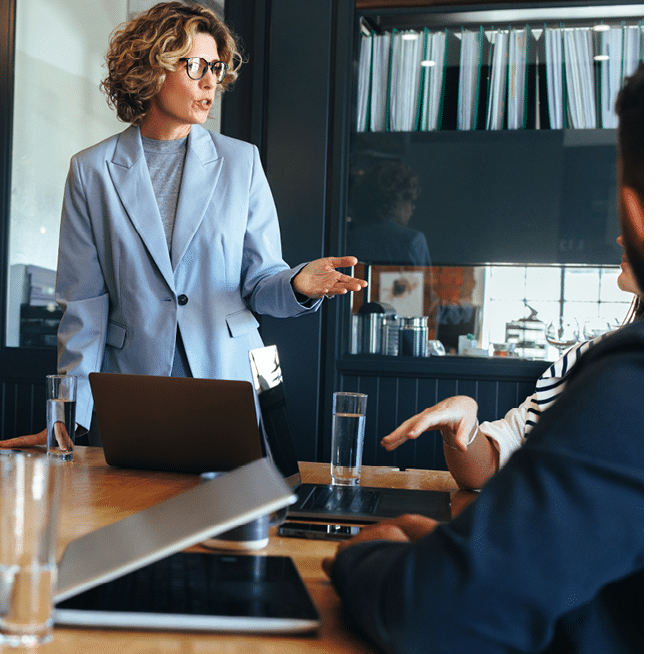 Business woman presenting an idea to her team in a meeting. Female manager having a discussion with her colleagues in a boardroom. Tech professionals working in an office.