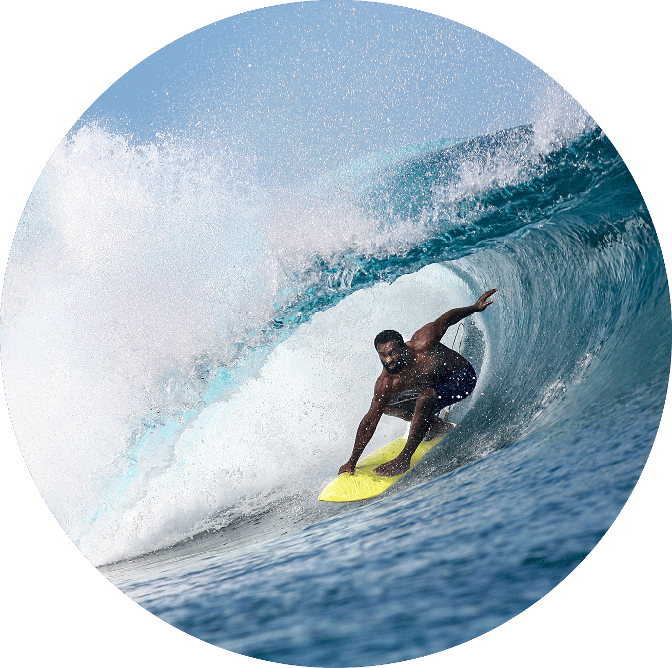 A fijian surfer rides under the lip of a breaking wave in Fiji