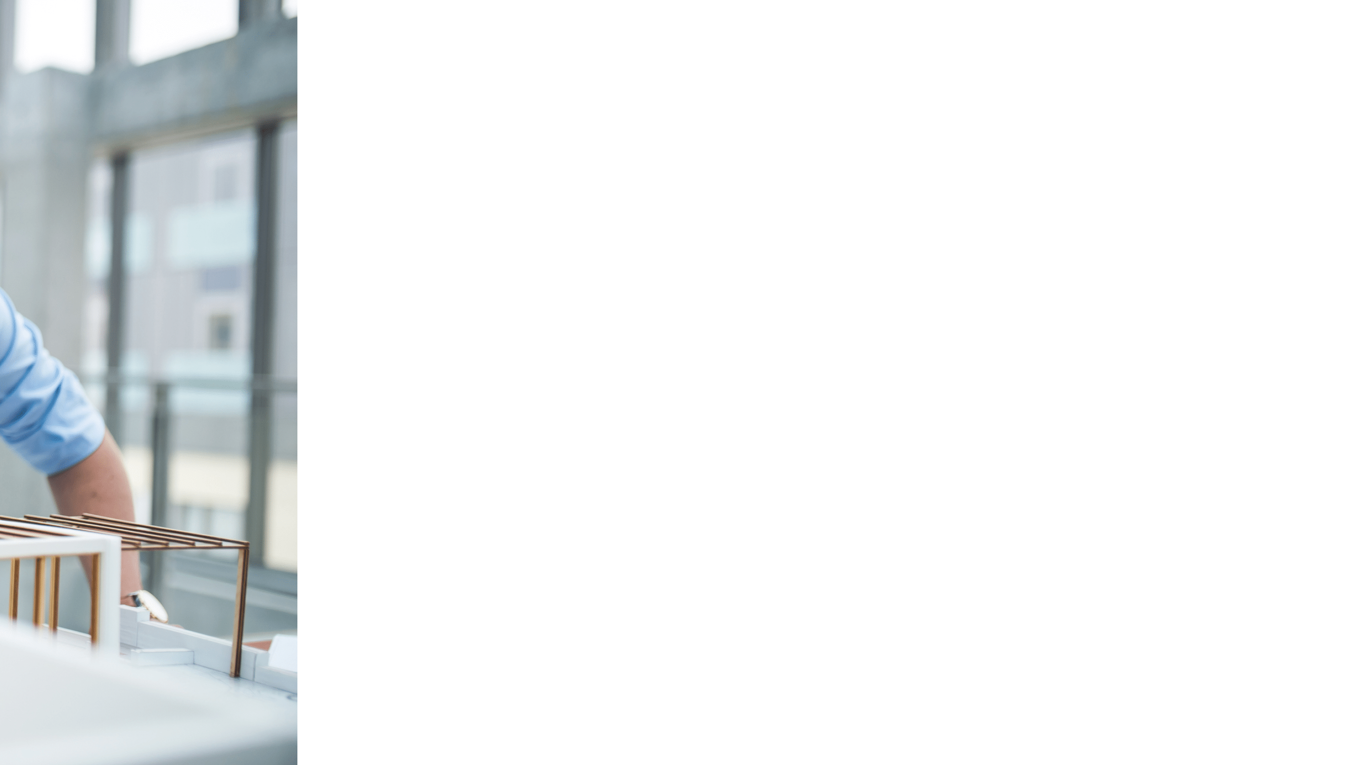 Young businessman or architect with model of a house standing at the desk in office, working 