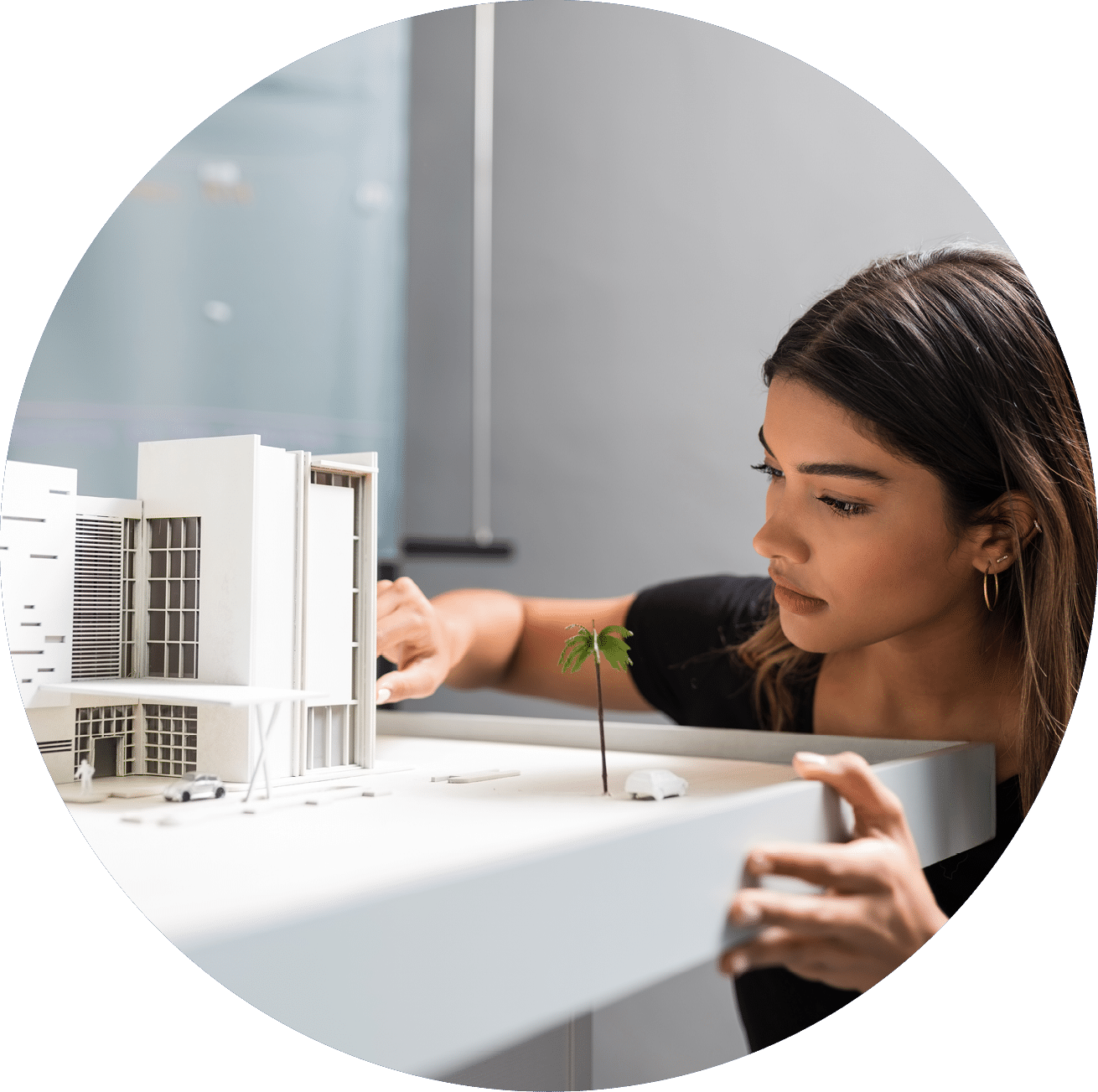 Young good looking female engineer analyzing model at desk in architect office